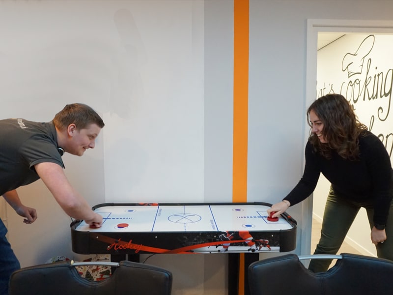Twee collega’s spelen airhockey op kantoor.