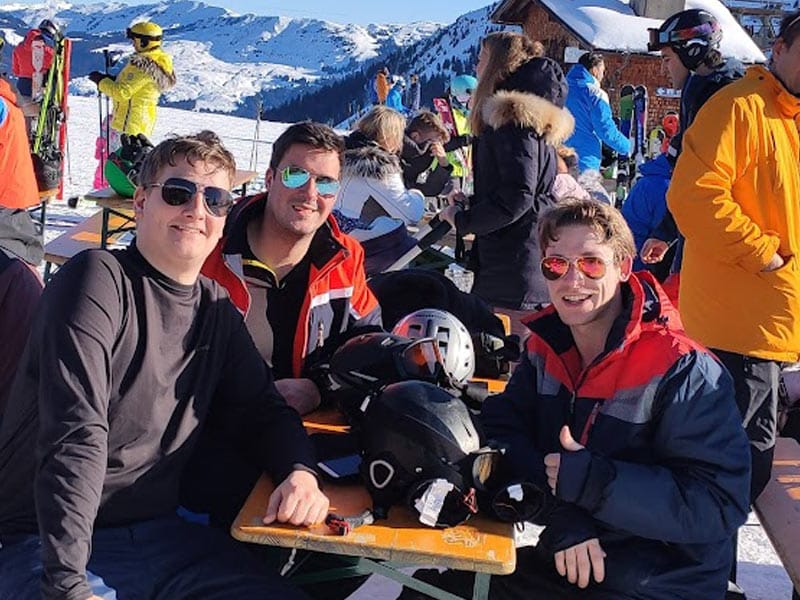 Collega’s zitten tijdens een teamreis op een terras in de sneeuw.