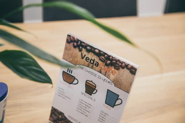 De VedaCafé-koffiekaart op een houten tafel.