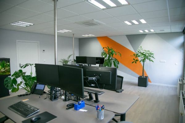 Werkplekken met beeldschermen en planten op kantoor.